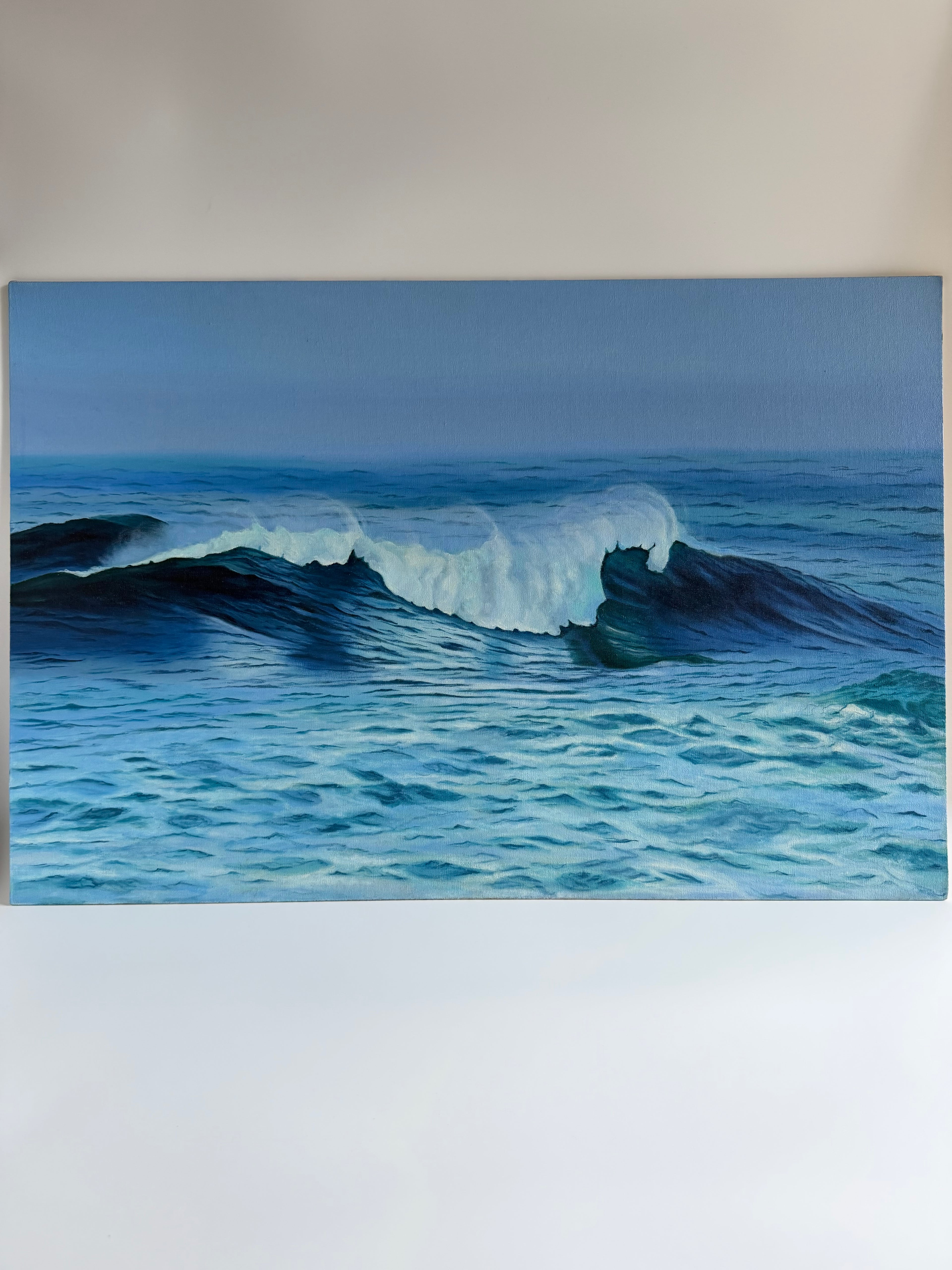 Original ocean wave oil painting featuring crashing waves and calming blue coastal waters.